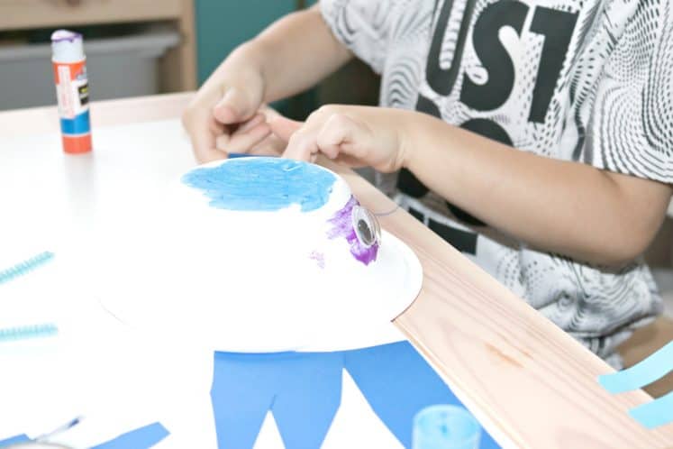 preschooler using paper bowl and cardstock to make whale craft